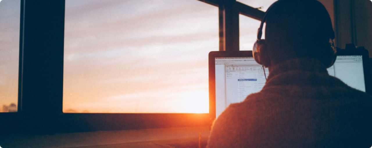 person on computer with sunset in background